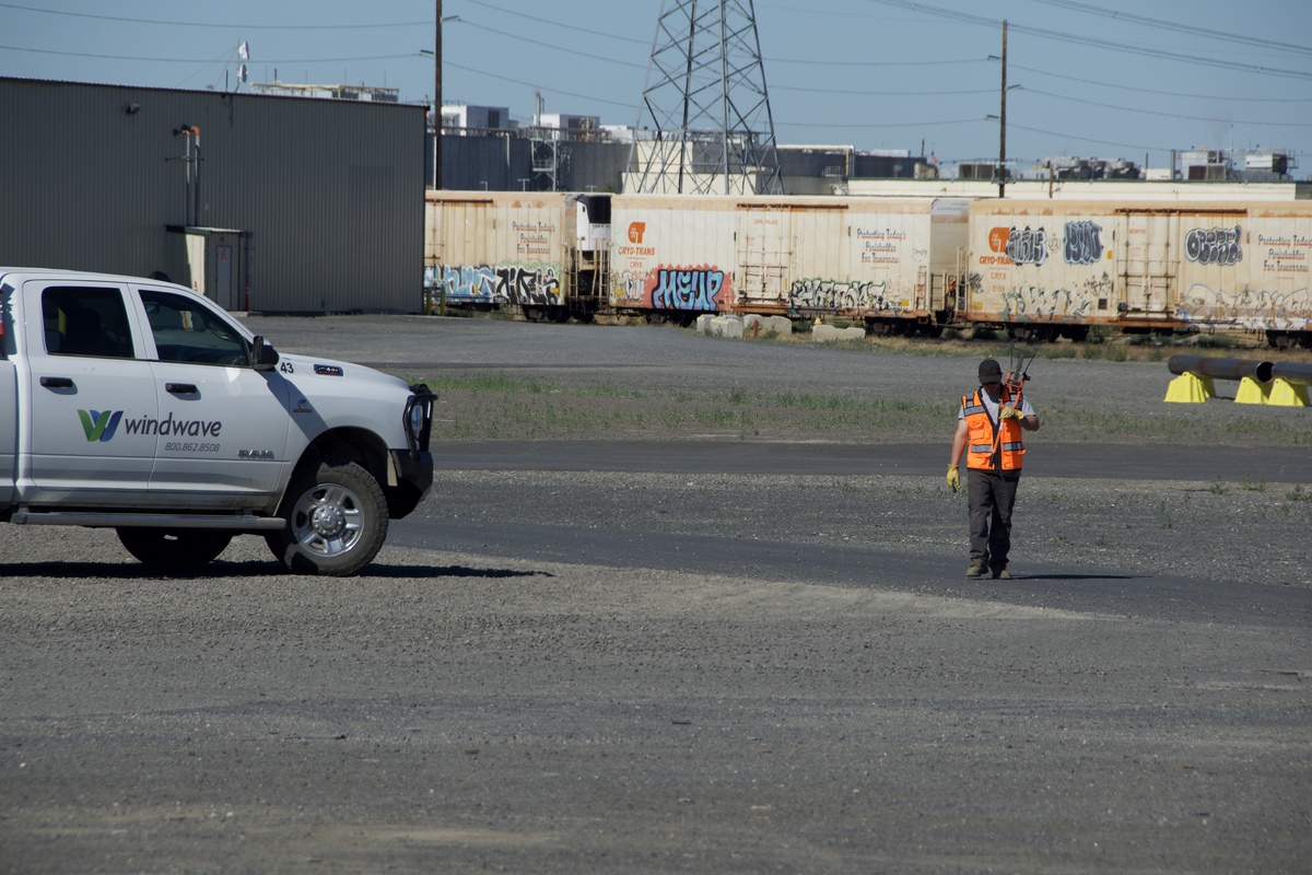 Windwave truck and a worker in high-visibility gear locating utilities in a rail yard