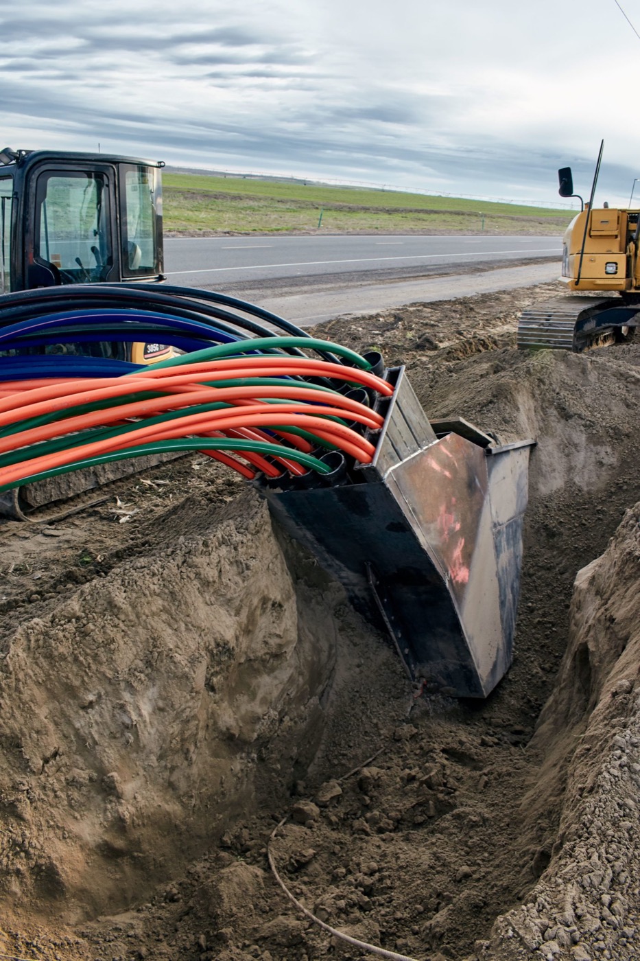 Bundled conduit ducts curving down into an open trench